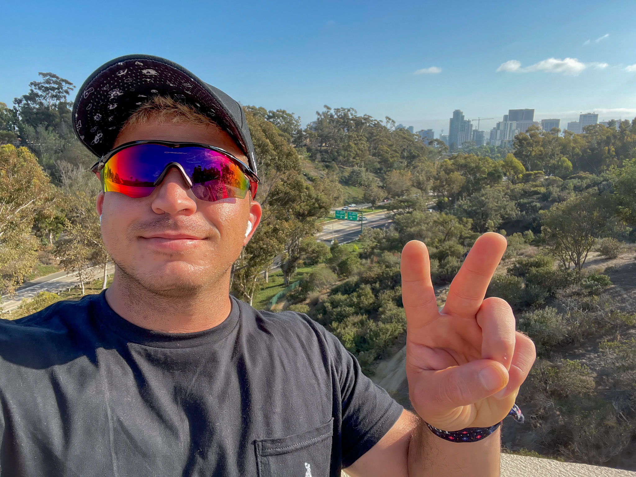 Hermz Shamoun at a Balboa Park overlook with the San Diego skyline behind him