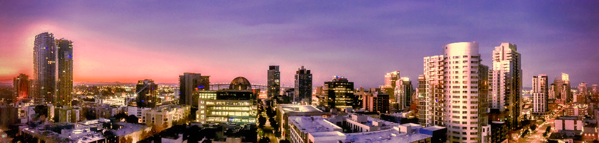 Panoramic view of a city skyline with illuminated buildings under a gradient purple and pink twilight sky.